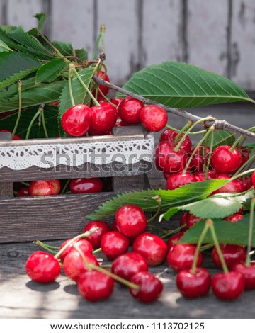 Cherries with leaves in vintage wooden box on rustic wooden table. Copy space.