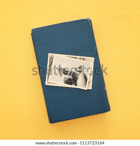 top view of photos over old book on yellow wooden background
