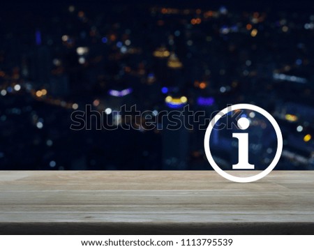 Information sign icon on wooden table over blur colorful night light modern city tower, Customer support concept