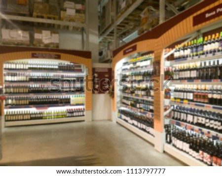 Blurred image of wine shelves display in supermarket. Defocused Rows of Wine Liquor bottles on the store shelf. Alcoholic beverage abstract background. Alcohol drink market concept. Royalty-Free Stock Photo #1113797777