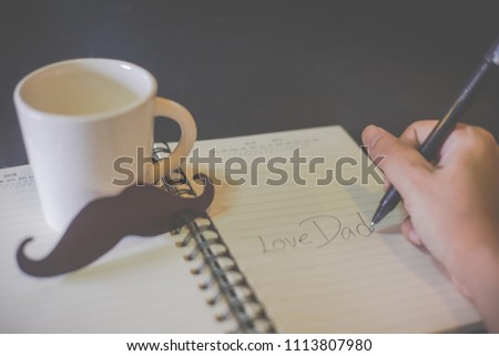Everyday is father's day. Not a single day I stop loving you. Happy Father's day concept. Human hand is writing Love Dad on the book over black background.