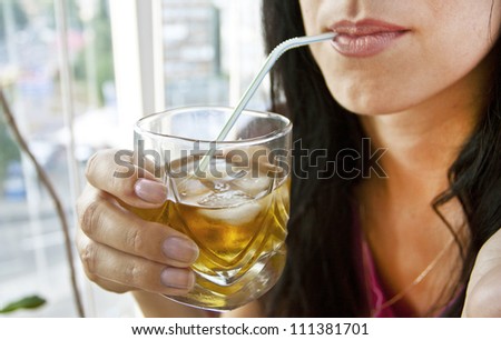 The woman drinking cocktail with ice from a tubule