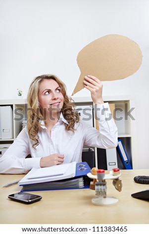 Attractive blonde woman holding empty speech balloon in the office