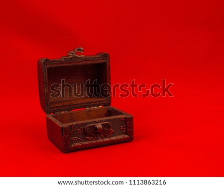 Miniature vintage treasure chest isolated on a red background image with copy space in landscape format
