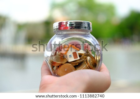 House model and coins in ball shaped container