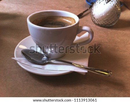 Breakfast in the cafe. Cup of Americano coffee in white mug, saucer and spoon. Close-up photo.