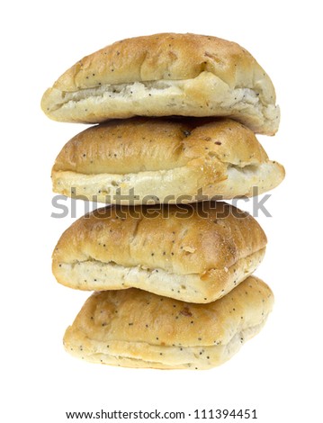 Four poppy seed and onion flavored square sandwich rolls in a stack on a white background.