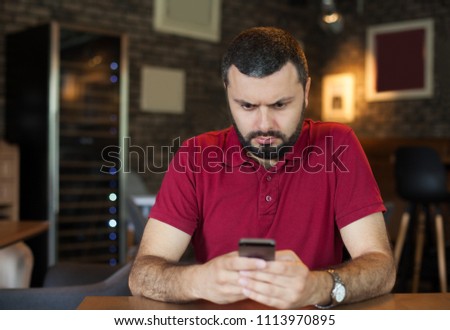 Young angry man typing on mobile phone