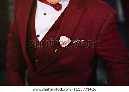 Groom in stylish red suit  wedding bridal bouquet of red, white, pink flowers and greenery, with a ribbon of color Marsala
and blur picture Royalty-Free Stock Photo #1113971426
