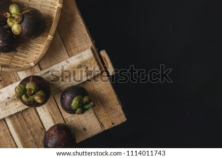 Mangosteen and cross section showing the thick purple skin and white flesh of the queen of fruits, Delicious mangosteen fruit on wooden box. Top view