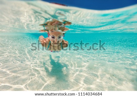 Underwater photo of a little girl swimming in tropical ocean