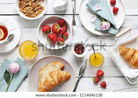 Breakfast food table. Brunch set, meal variety with fried egg, croissants, granola and fresh strawberry. Overhead view