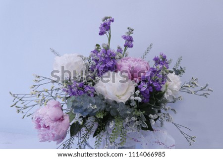 Bouquet of peonies and lilac mattioli in a round high box.
