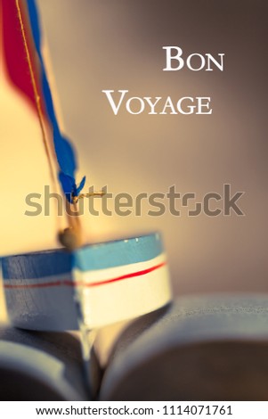 Background picture with toy sailboat between the wavy pages of open book and wish for good journey - bon voyage (copy space)