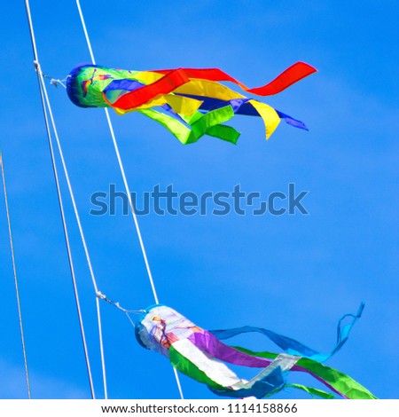 Bright Blue Sky and Two Colorful Windsock flags flying high at the Marina Royalty-Free Stock Photo #1114158866