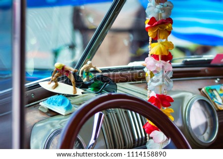 Hawaiian pink, red, blue orange, Lei in a vintage Woody Car with Surfers and Sunglasses at a fun car show. Royalty-Free Stock Photo #1114158890