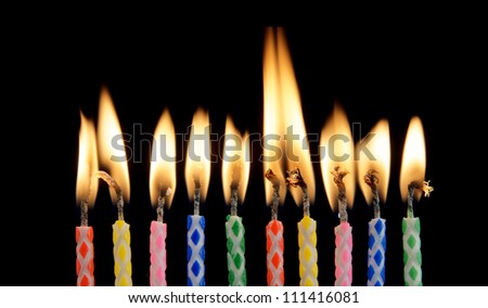 Ten burning candles on black background
