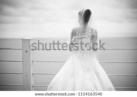 Beautiful bride picture wearing white bridal in black and white face to the ocean