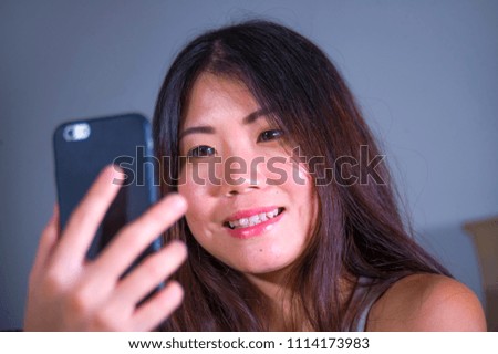 young sweet happy and pretty Asian Korean girl taking selfie picture with mobile phone for internet social media on mobile phone laughing at home in online communication lifestyle concept