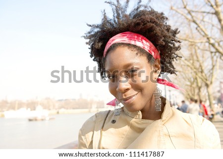 Portrait of an attractive african american woman sightseeing in London's river Thames while on vacation, smiling.