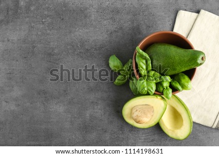 Flat lay composition with ripe avocados and basil on grey background