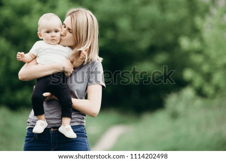Happy loving mom hugging and kissing her adorable little baby daughter. Mother and child walking in nature. Family, motherhood and lifestyle concept.