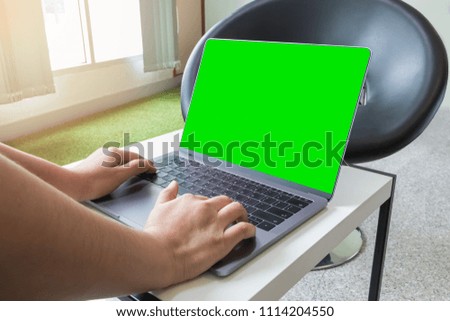 Woman typing on keyboard laptop computer and green screen with clipping path on screen for insert other objects.