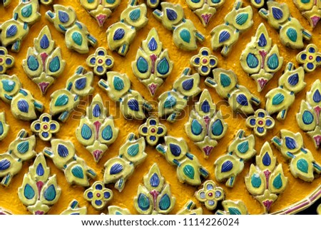 Traditional ceramic mosaic art with flower patterns on yellow background                               