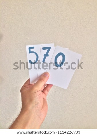 Handmade number that holding by hand on white paper.