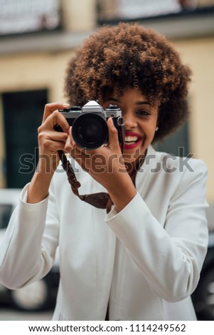 Female photographer visiting Madrid with an old analog camera. Afro race young woman, 21 years old.