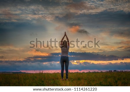 young girl in a field during a colorful bright summer sunset. The concept of freedom, will, nature