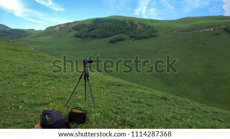 Camera on a tripod, shooting green mountains scenery