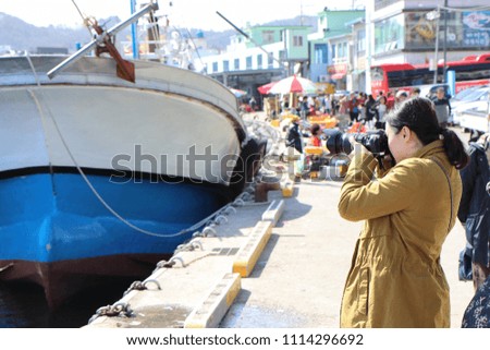 Asian waman photographer taking pictures of fishing boat, Korea east sea 
