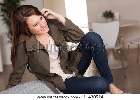 Beautiful young Caucasian female relaxing on grey chair at home with long brown hair.