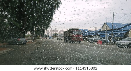 Blured background with rains drop on glass and cars on the road, Road view through car window blurry with heavy rain, Driving in rain, rainy weather