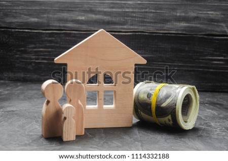 Wooden figures of the family stand near a wooden house and collapsed money. Buying and selling a house. Good life, moving to new apartments. Realtor services. A happy family.