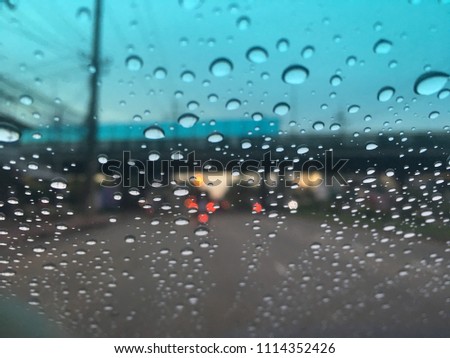 Defocused image, raindrops on the windshield, traffic in the city on a rainy day at evening, car windshield view, colorful bokeh.