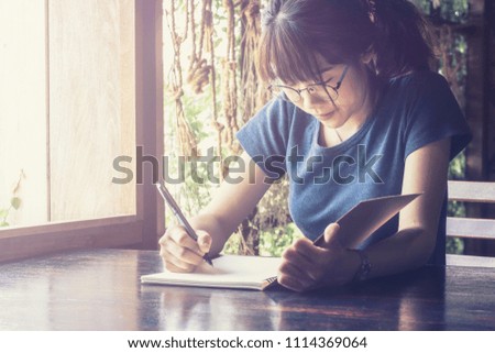 Asian woman student use pen write message on book after education out time.color tone