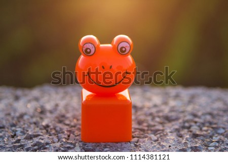 smiling frog face, orange plastic toy