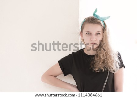 girl posing on a white wall with a bow on her head