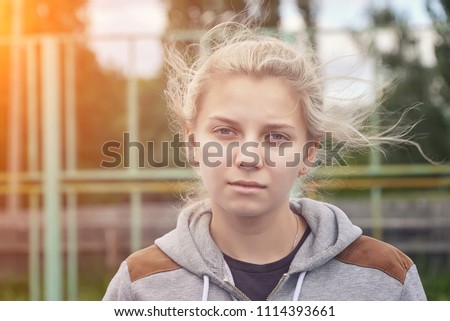 portrait of a shaggy girl in windy weather on a background of a sports fencing of a platform