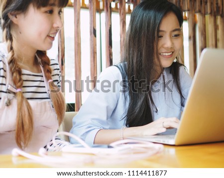 Teamwork girls, modern Asian young generation using laptop for online working or tutoring for special education at nice internet cafe or coworking space. Technology's impact on people's lives concept.