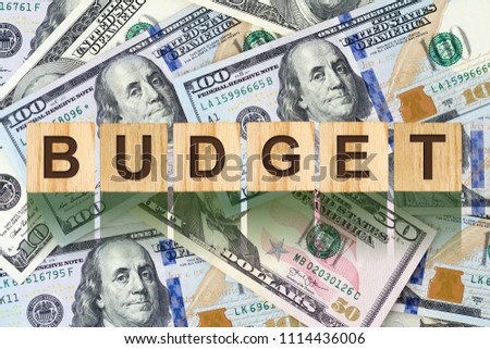 Word, Budget composed of letters on wooden building blocks against the background of dollar bills. Concept business, finance. Backgrounds.