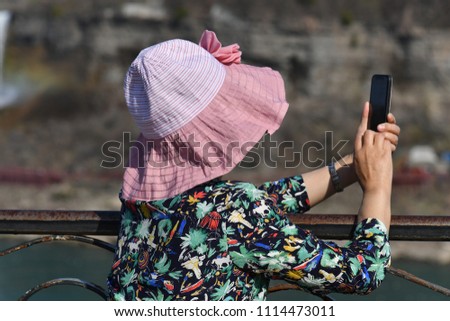 A chinese woman takes a picture of the Niagara-Falls in Camada