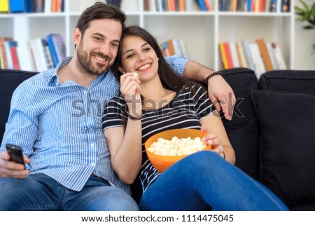 Young couple watching tv at home and having fun Royalty-Free Stock Photo #1114475045