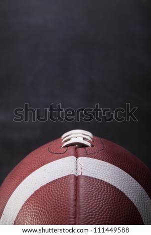 An American football with a chalkboard in the background for copy-space.