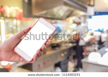 Man use mobile phone, blur images of chef cooking in the restaurant as background.