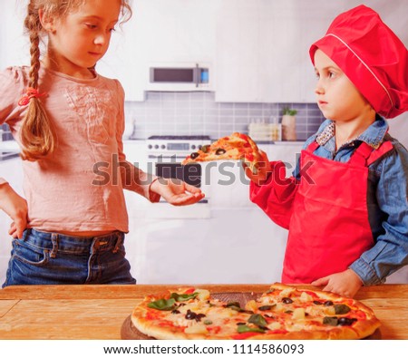  Funny happy chef girl treats pizza other little girl. Humorous photo.