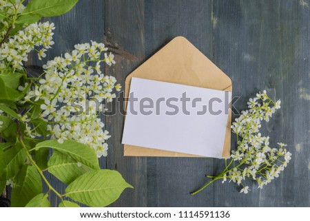 Mockup white greeting card and envelope with white spring flowers and rustic wooden background