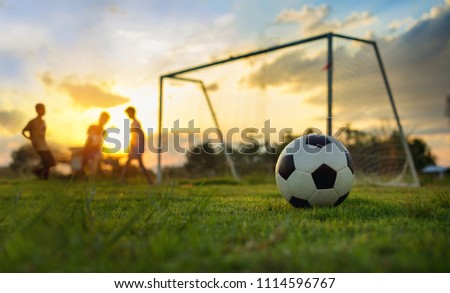Silhouette action picture of a group of kids playing soccer football for exercise in community rural area under the sunset. For world cup trend concept.